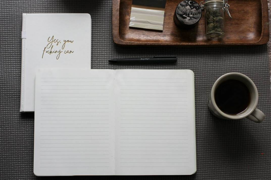 Top view of a desk with an open notebook, pen and coffee cup
